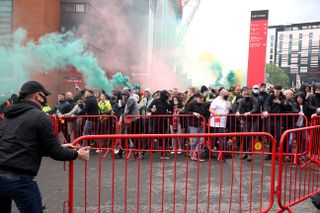 Fans move barriers outside Old Trafford as they let off flares