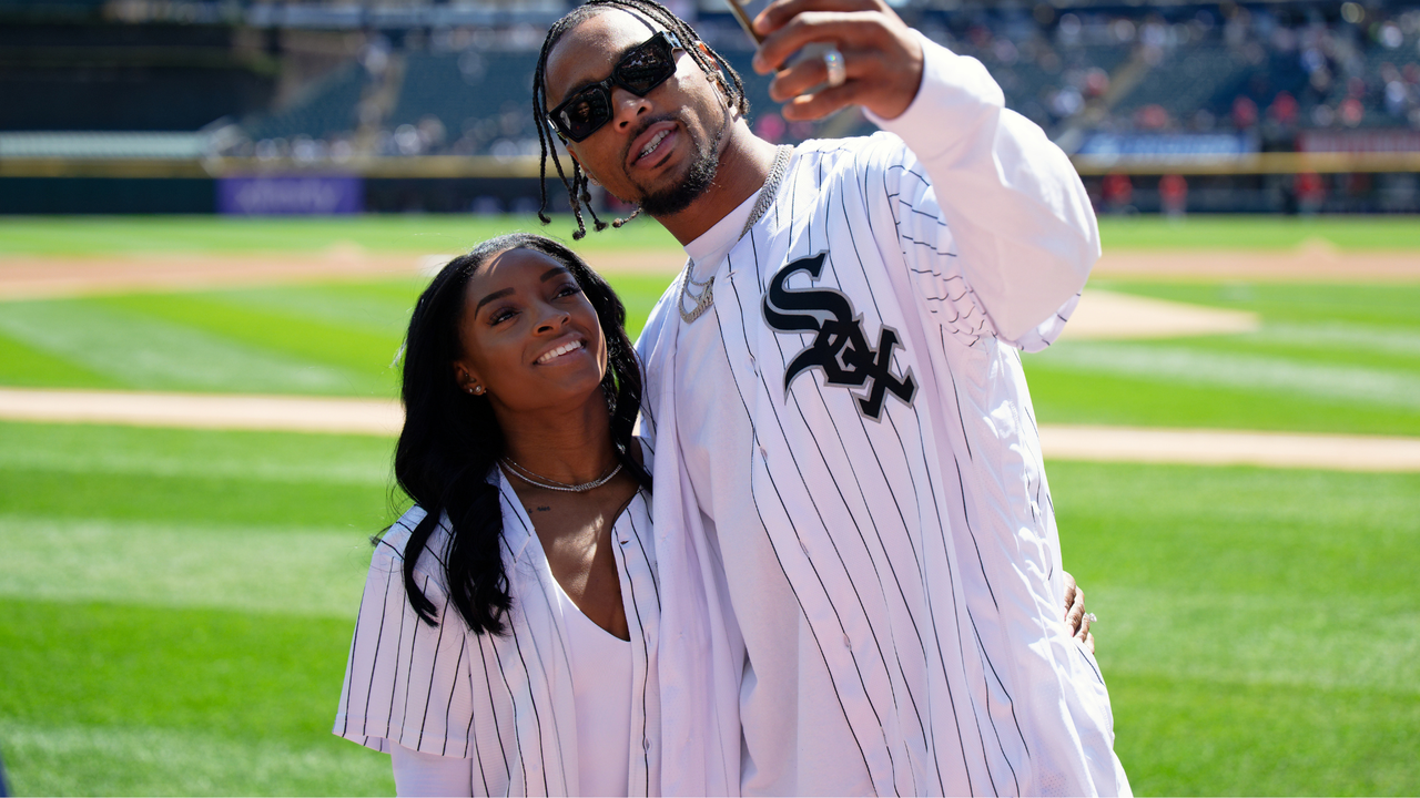 Gymnast Simone Biles and Jonathan Owens of the Chicago Bears record a video on the field before Owens threw out a first pitch before a game between the Cincinnati Reds and the Chicago White Sox at Guaranteed Rate Field on April 13, 2024 in Chicago, Illinois