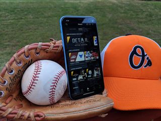ESPN Plus on iPhone app in baseball glove next to baseball cap