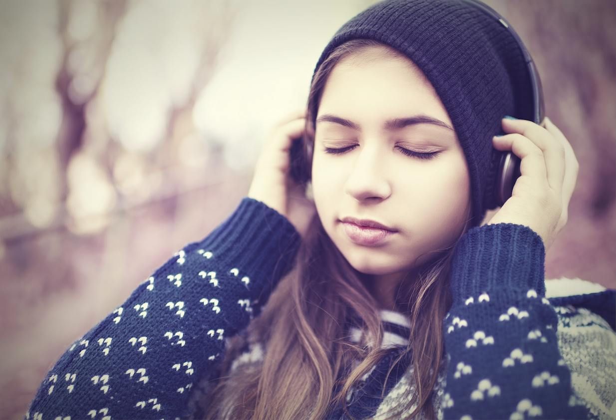 teenage girl in headphones listens to music with closed eyes