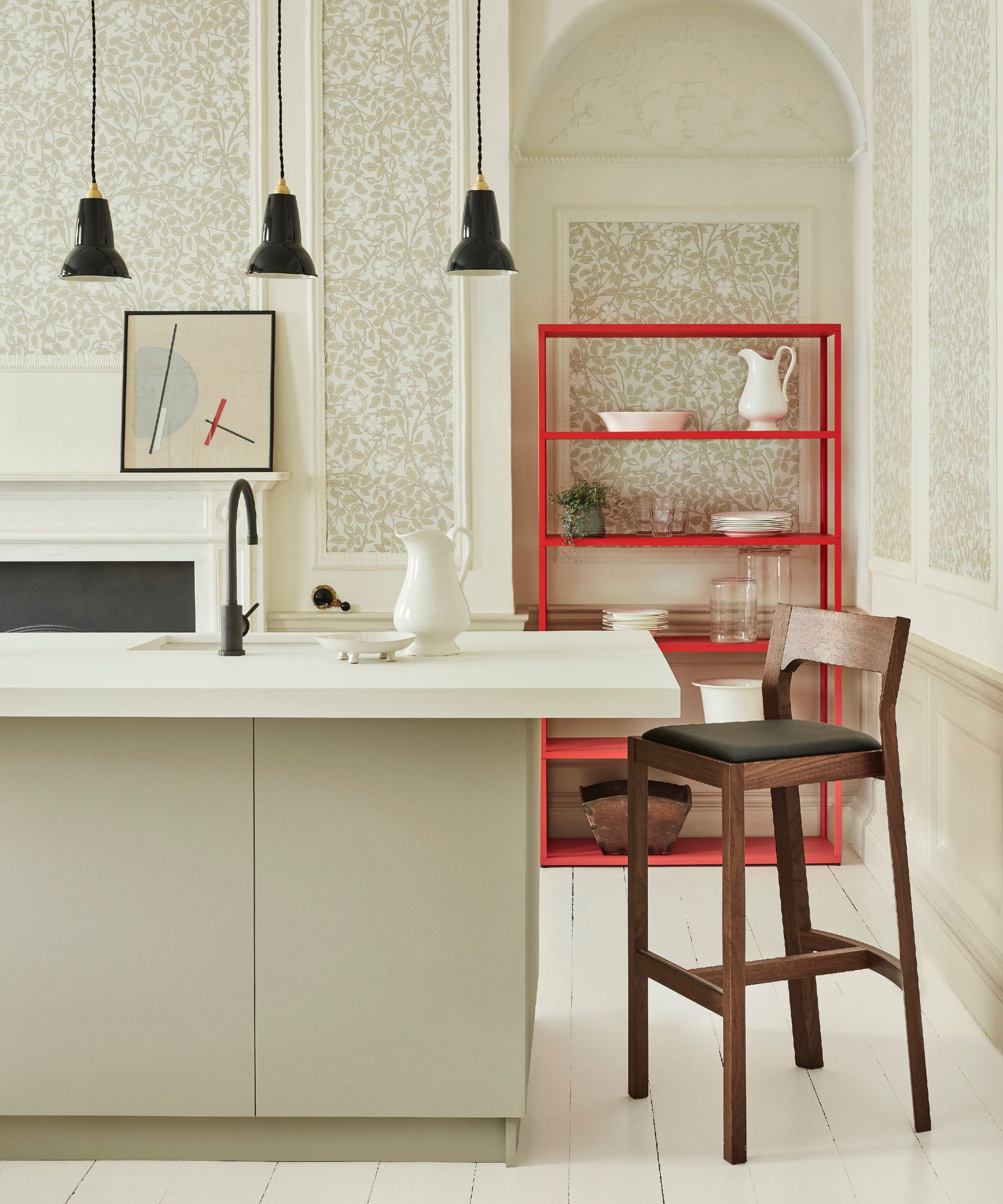accent colors for a white kitchen, white kitchen with damask style wallpaper, kitchen island, black trio of small pendants, red shelving unit, white floor