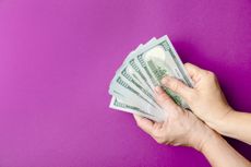 Image of person's hands holding a fanned out stack of cash.