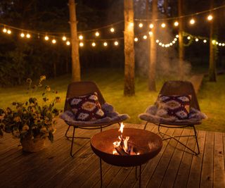 A fire pit and chairs with solar lights in the background