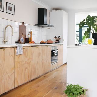 White kitchen with wooden floor and plywood cabinets