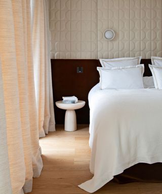 neutral hotel bedroom with a plush bedding set up and textured walls