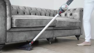 Using hoover to clean underneath sofa
