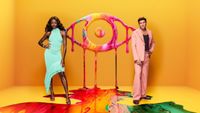 Big Brother hosts AJ Odudu and Will Best beside the show's new logo, an eye comprised of different paints of bright colors dripping onto the floor