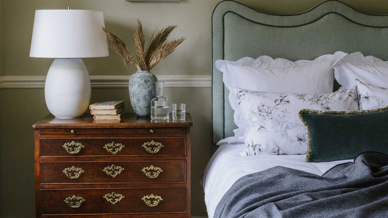 A dresser beside the Great River Headboard against a green wall. 