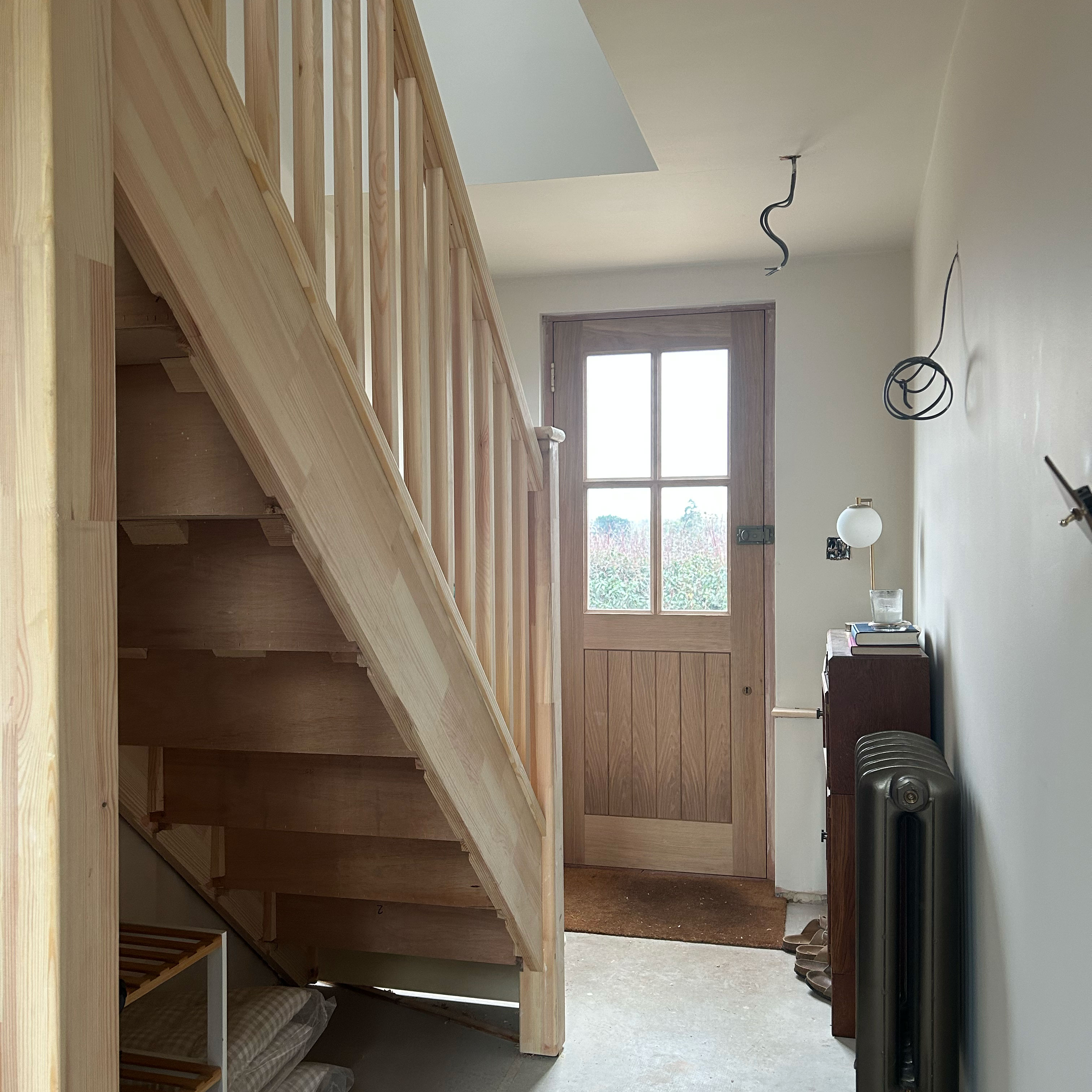 Entrance hall of a house after a major renovation, with unfinished stairs and exposed wiring