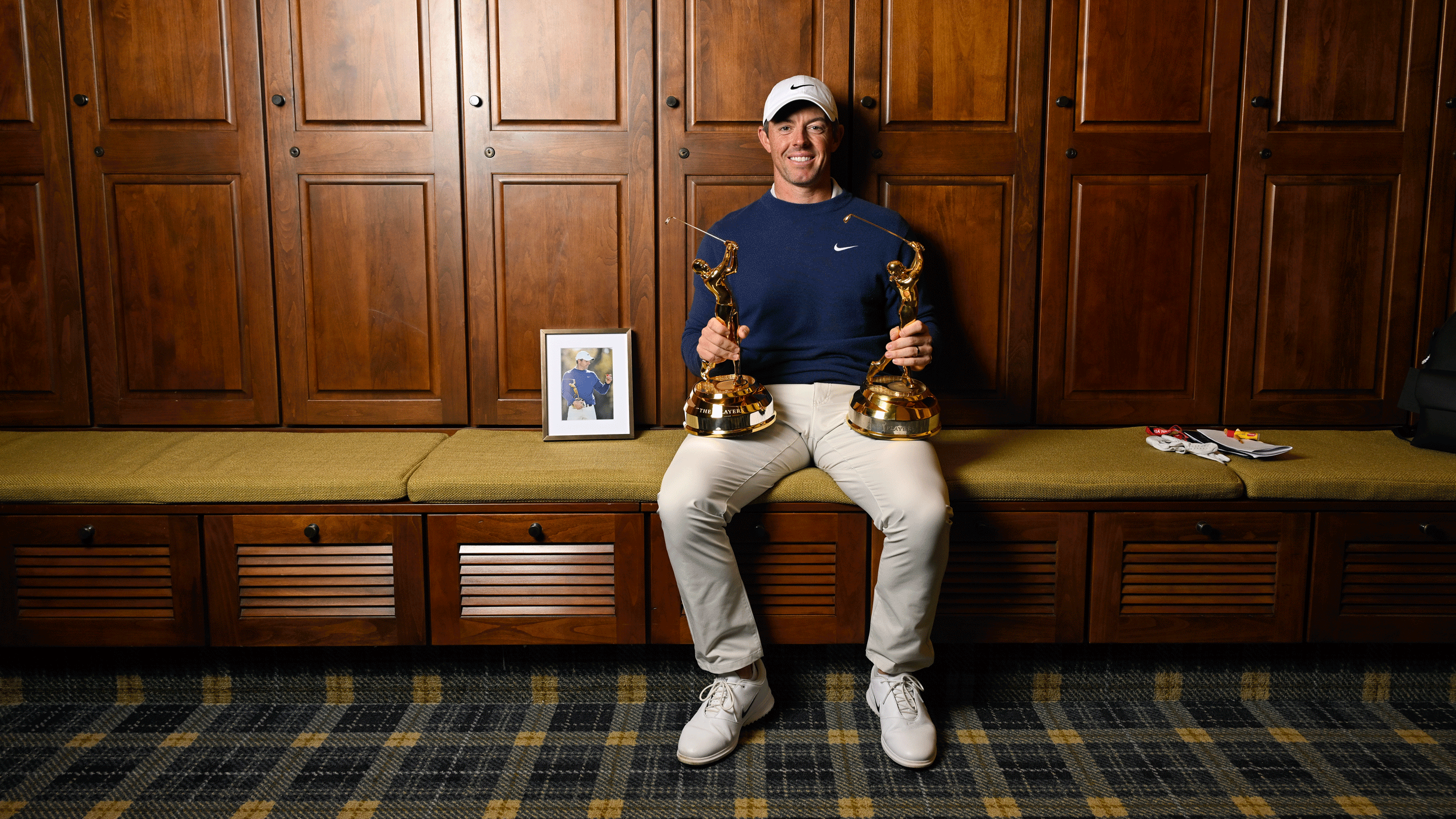 Rory McIlroy sits in the locker room at TPC Sawgrass with his two Players Championship trophies resting on his legs