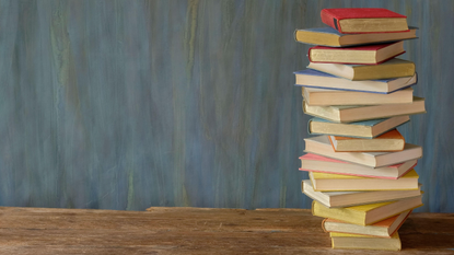 Pile of books on a wooden table.