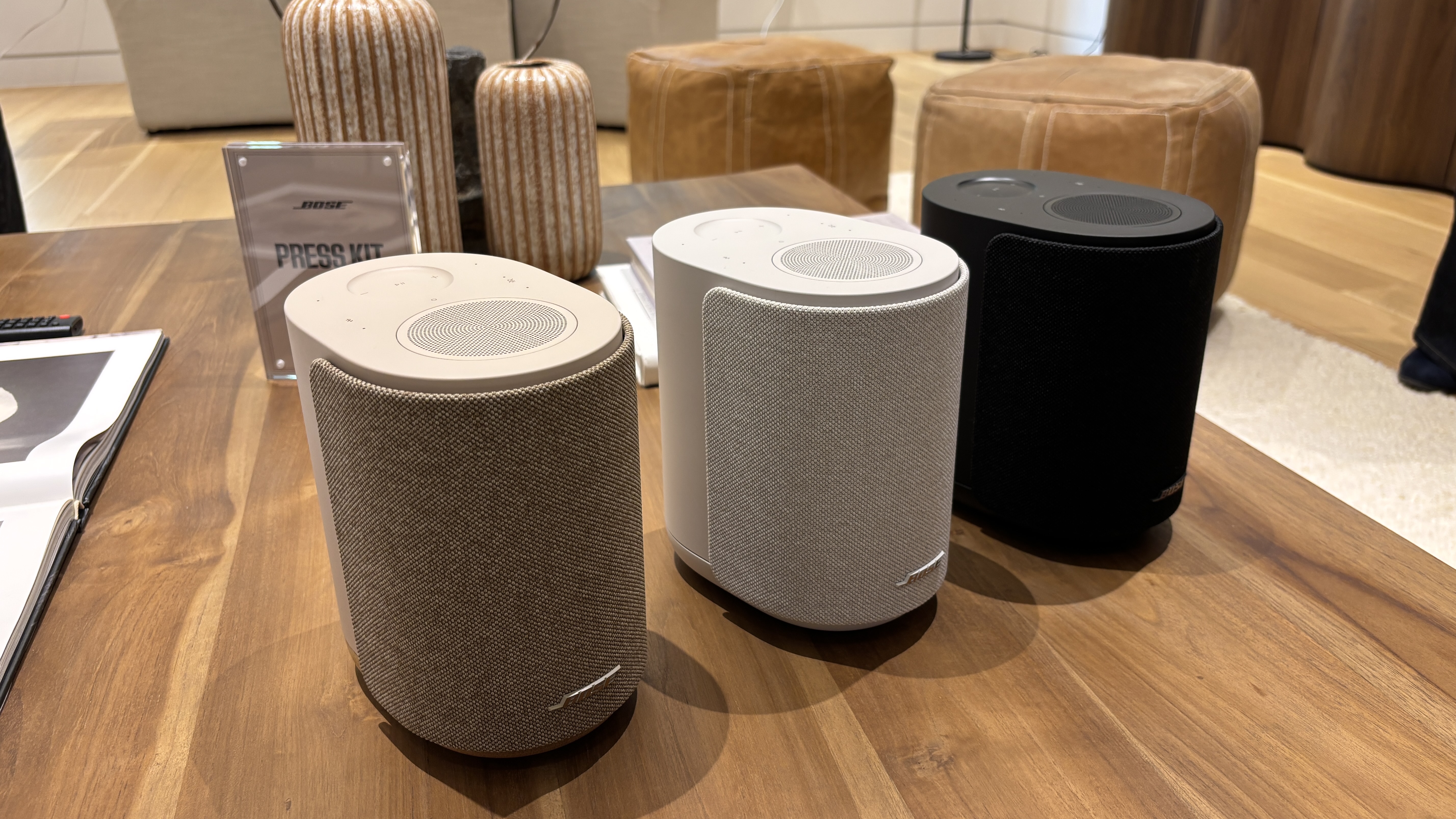 Bose Lifestyle Ultra Speakers in black, smoke white and 'Driftwood Sand' arranged in a row on a table