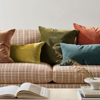 Yellow blue orange and brown throw pillows on neutral plaid sofa