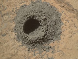 NASA's Curiosity Mars rover completed a shallow "mini drill" test April 29, 2014, in preparation for full-depth drilling at a rock target called "Windjana." This image from Curiosity's Mars Hand Lens Imager shows the hole resulting from the test, 0.63 inch across and about 0.8 inch deep.