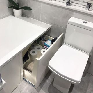 under bath drawer storage in a white bath next to a white toilet