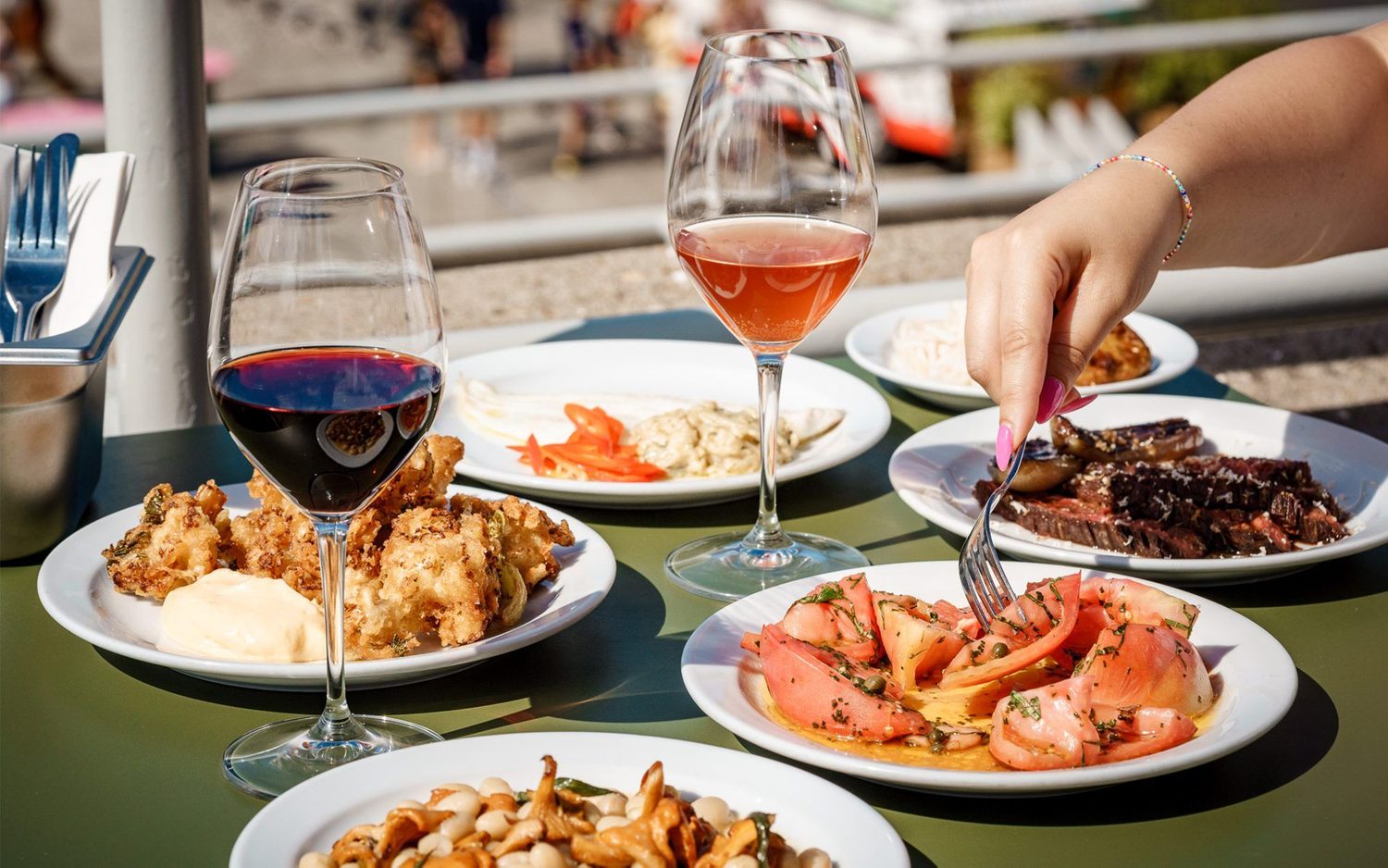 Dishes of food and two glasses of wine on an outdoor table