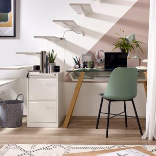 home office with stairway and laptop on desk with chair