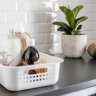 White storage basket filled with bathroom products on top of countertop