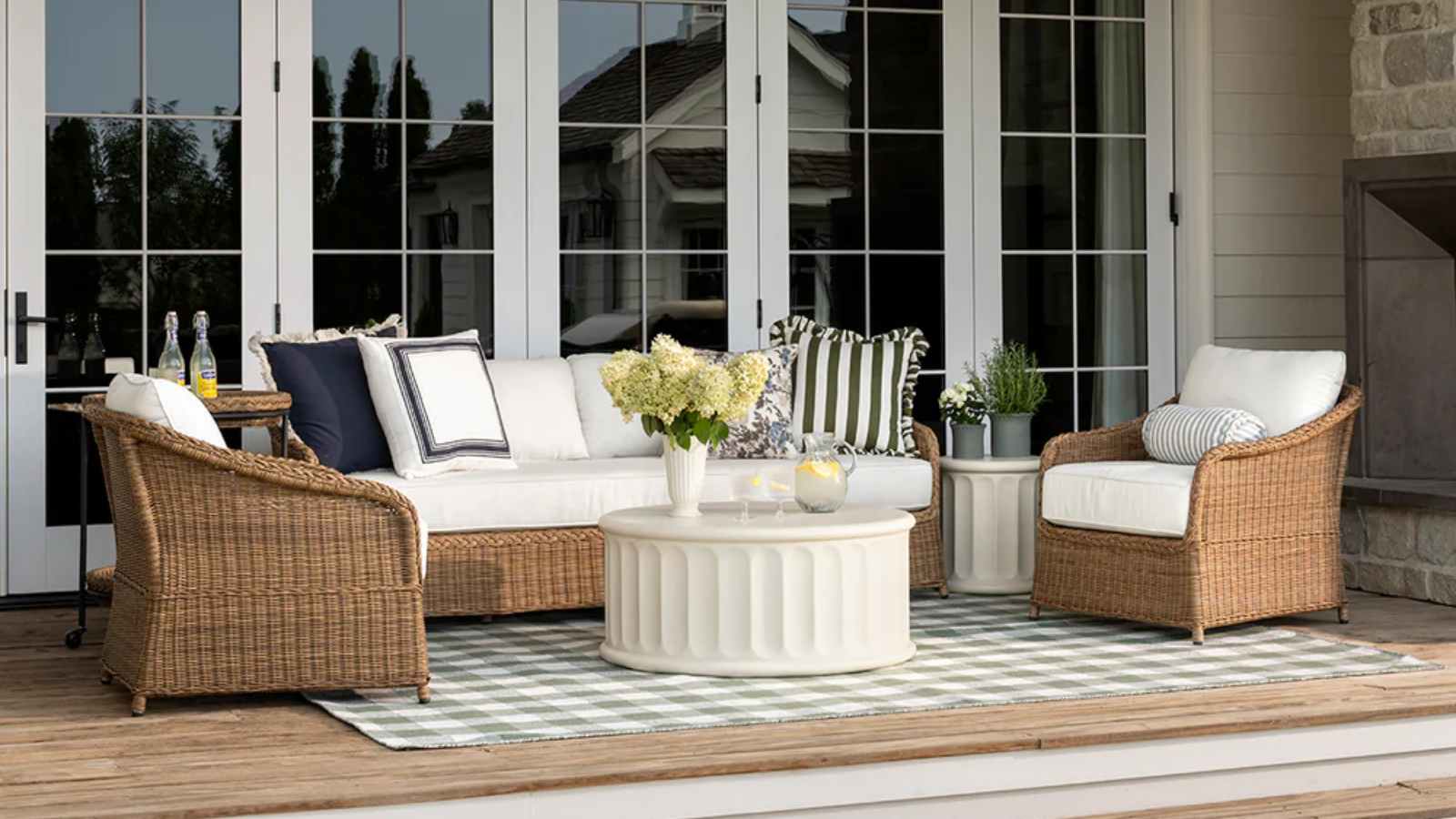 an outdoor living room with a couch, two chairs, and a coffee table