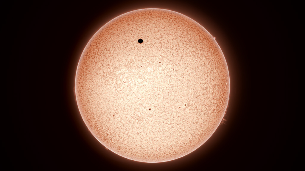 Venus' apparent width was about 3% that of the sun and easily visible with regular eclipse viewers. This image shows the full solar disk through a dedicated Hydrogen-Alpha (Hα) telescope, which reveals the sun's complex chromosphere.
