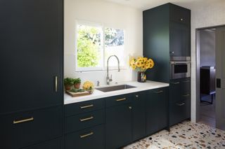 A kitchen with navy cabinetry and terrazzo flooring