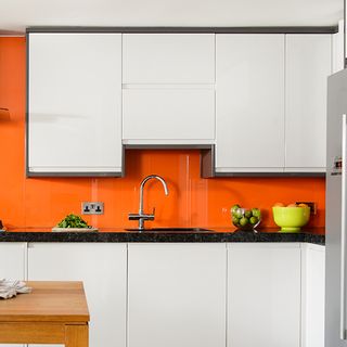 kitchen with orange wall and white cabinets