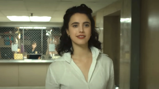 Margaret Qualley walking while smiling in button up white shirt in Honey Don't! 