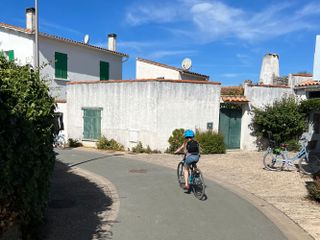 A child cycling the back lanes of Île de Ré with a blue sky above