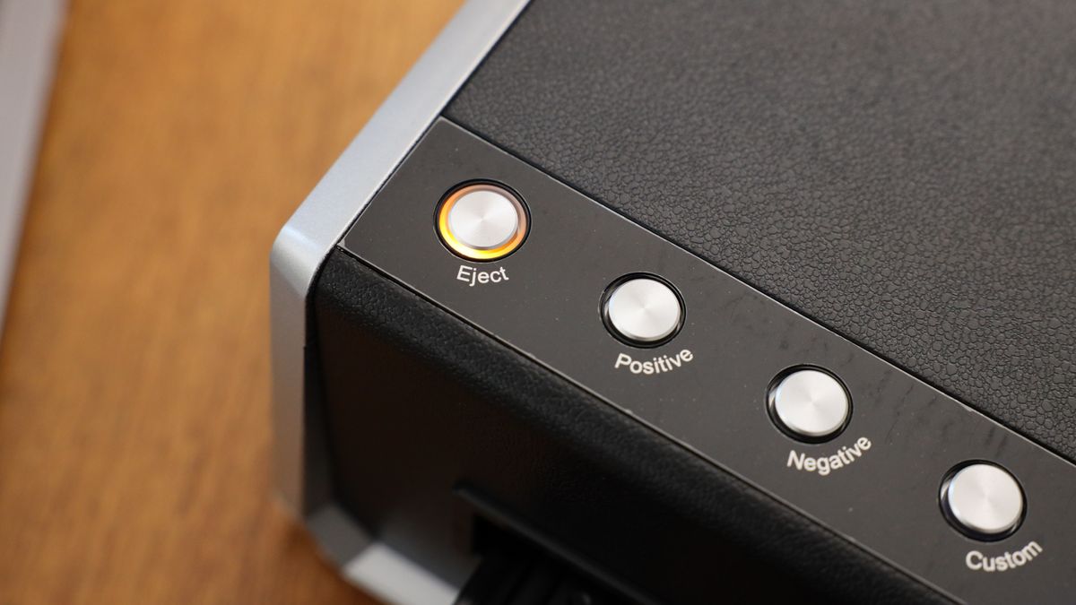 Close up of a button on the Plustek OpticFilm 135i on a wooden surface