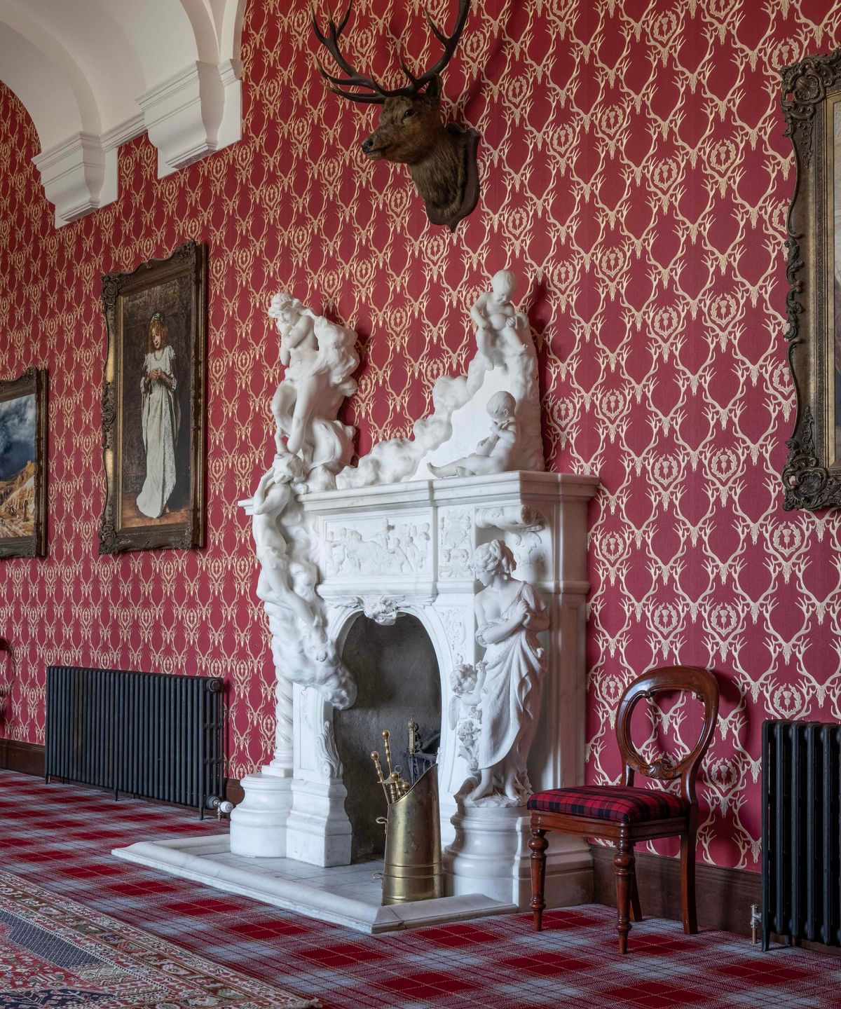 A VIctorian style fireplace with a deer head hanging above