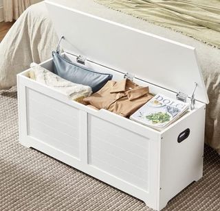 White storage chest at the foot of a bed