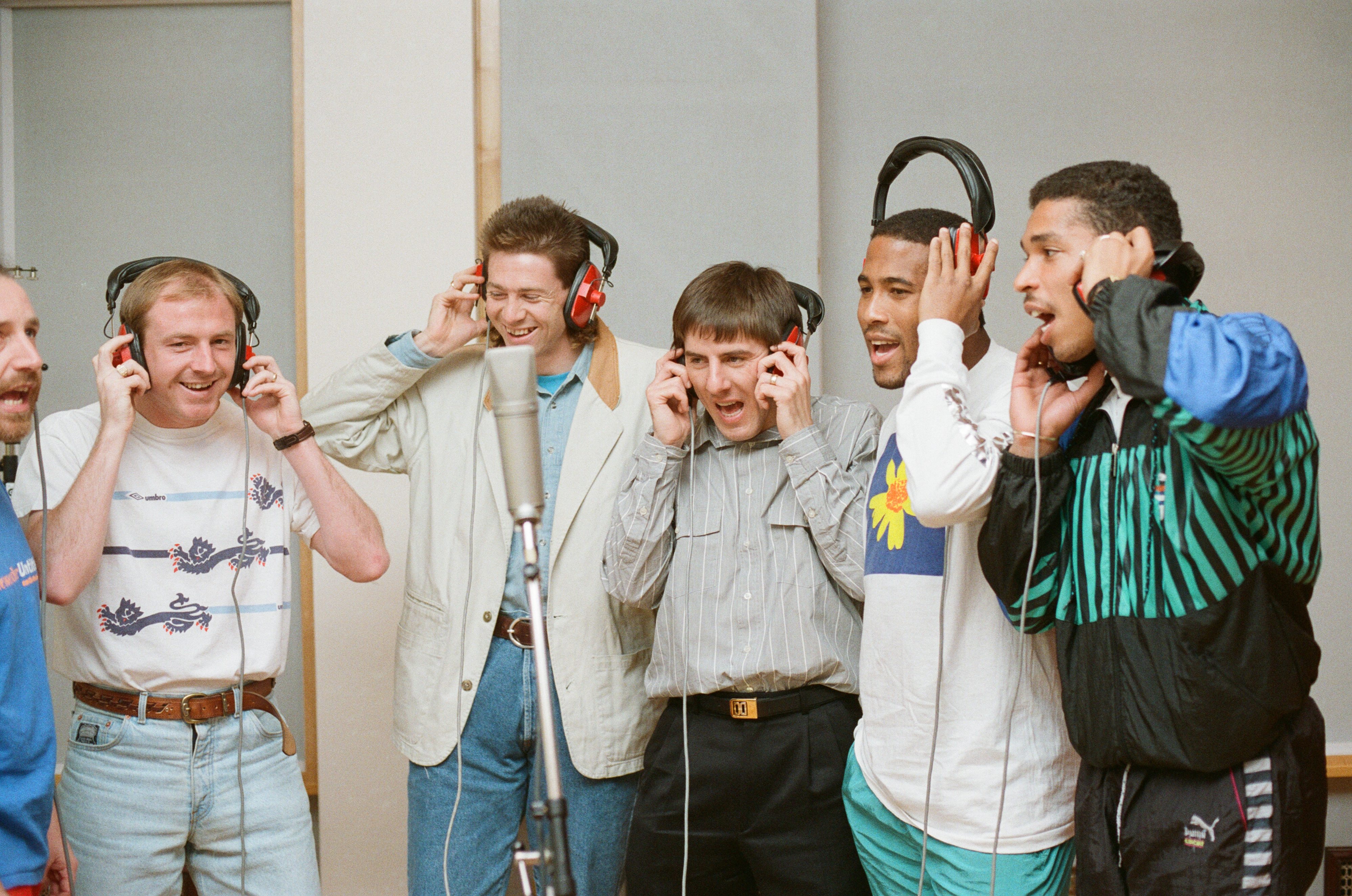 Steve McMahan, Chris Waddle, Peter Beardsley, John Barnes and Des Walker singing in a recording studio wearing headphones with New Order's bass player Peter Hook in 1990 for the recording of England's song 'World In Motion'