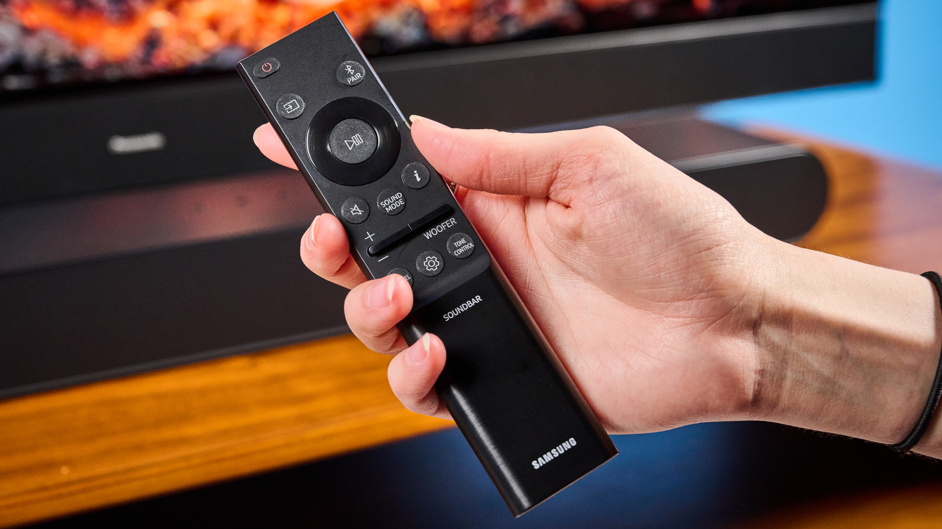 the samsung hw-s60D soundbar photographed on a wooden coffee table with a panasonic tv and a samsung soundbar against a blue background