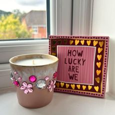 A bedazzled pink candle with pink and silver gems next to a pink matchbox