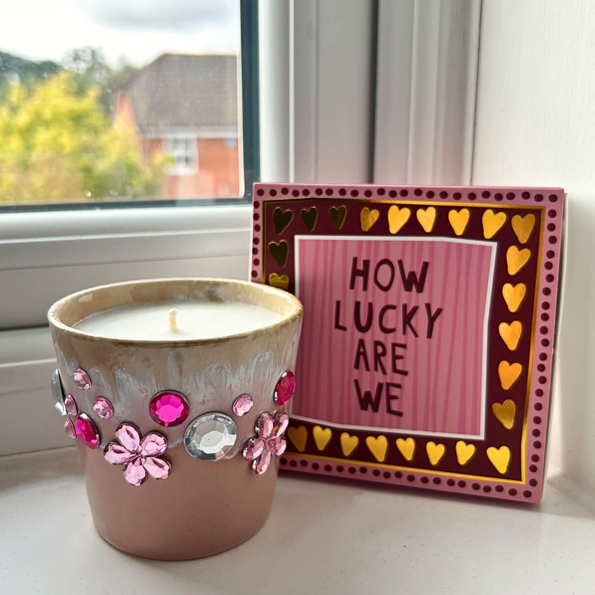 A bedazzled pink candle with pink and silver gems next to a pink matchbox