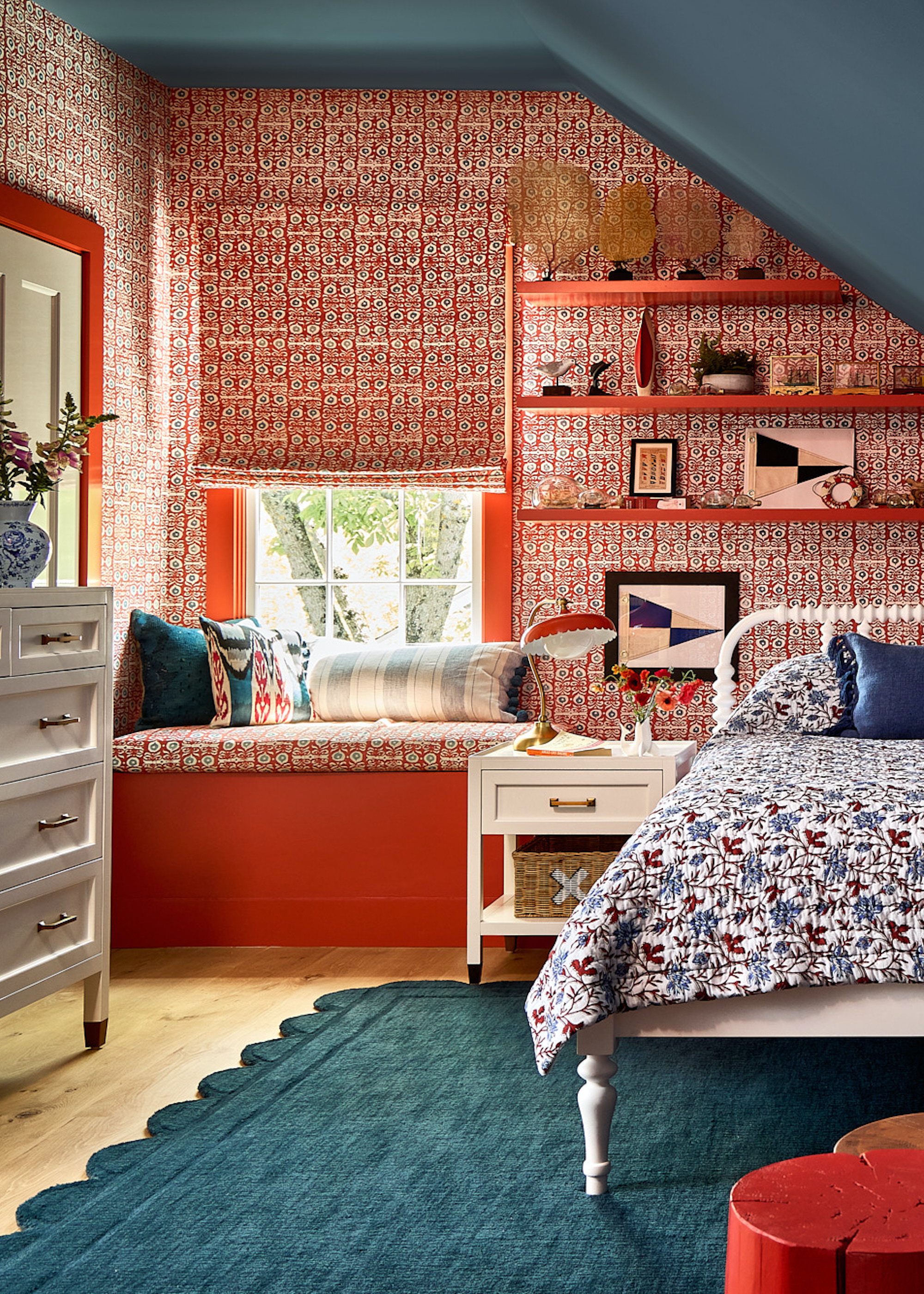 loft with bed and floating shelves, with patterned red wallpaper, and a blue painted sloped roof