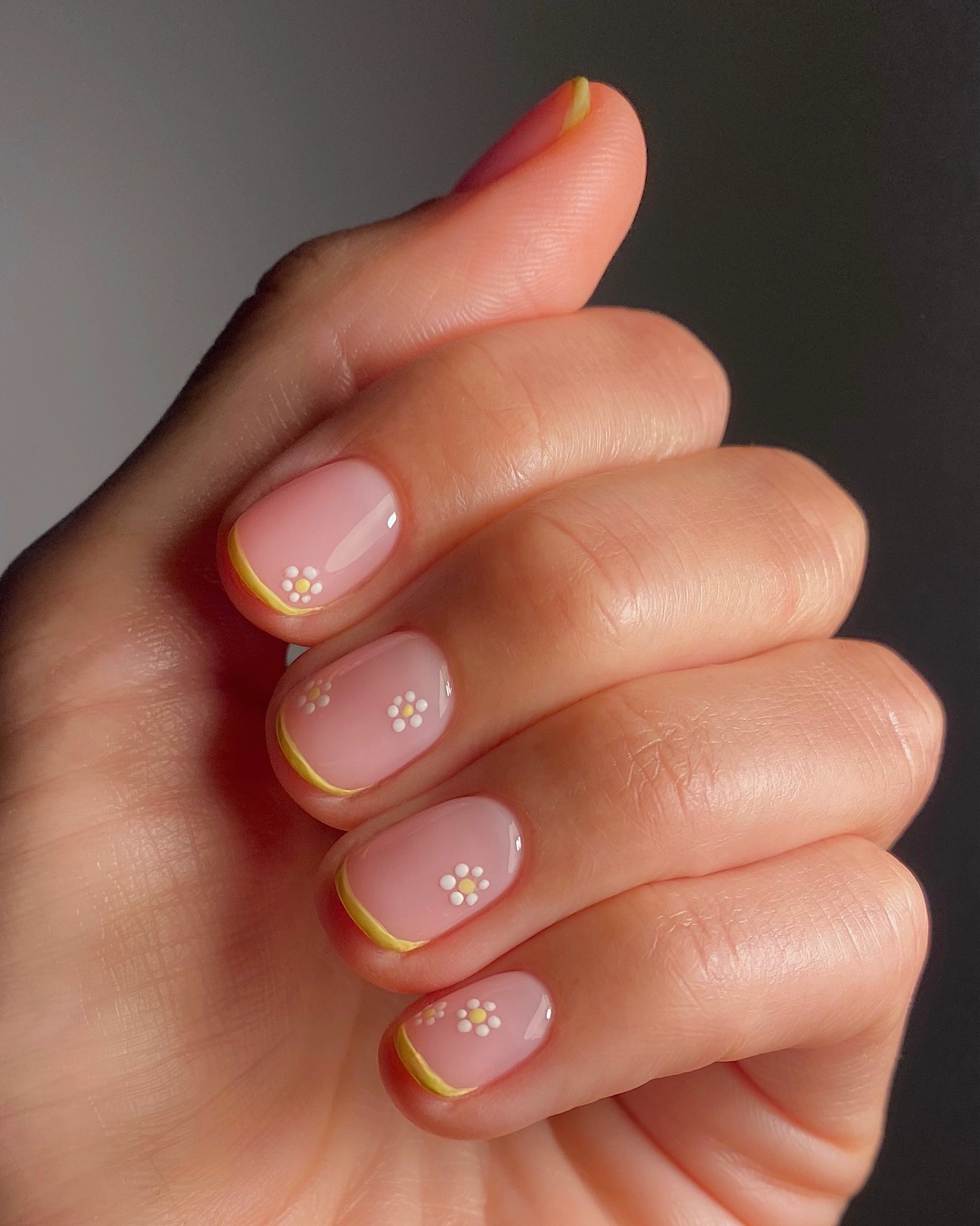 A yellow French tip manicure with mini yellow and white flowers