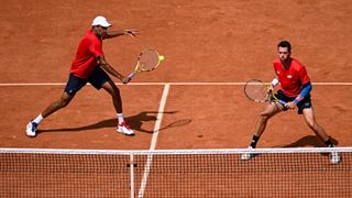 Rjeev Ram (L) and partner Austin Krajicek in red shirts and navy shorts playing in the men&#039;s doubles at the 2024 Olympic Games.