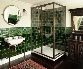 corner shower cubicle in bathroom with dark green tiled walls and traditional sanitaryware