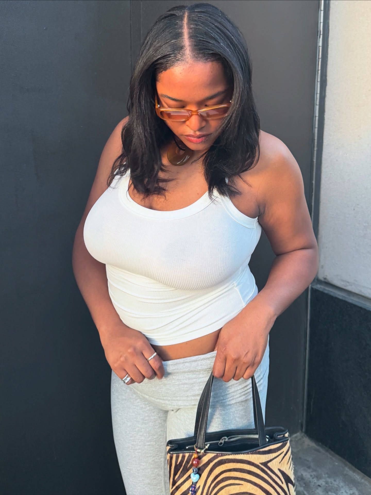 An image of @_imanirandolph wearing Adanola ultimate leggings in grey with a white tank top and tiger-print bag while in New York.