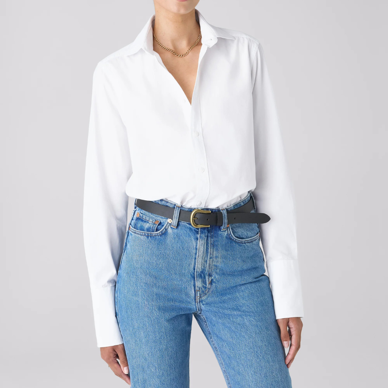 A woman wears a white shirt, blue jeans and belt