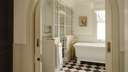 checkered marble floor bathroom with an arched doorway, freestanding tub and a conservatory-style shower enclosure
