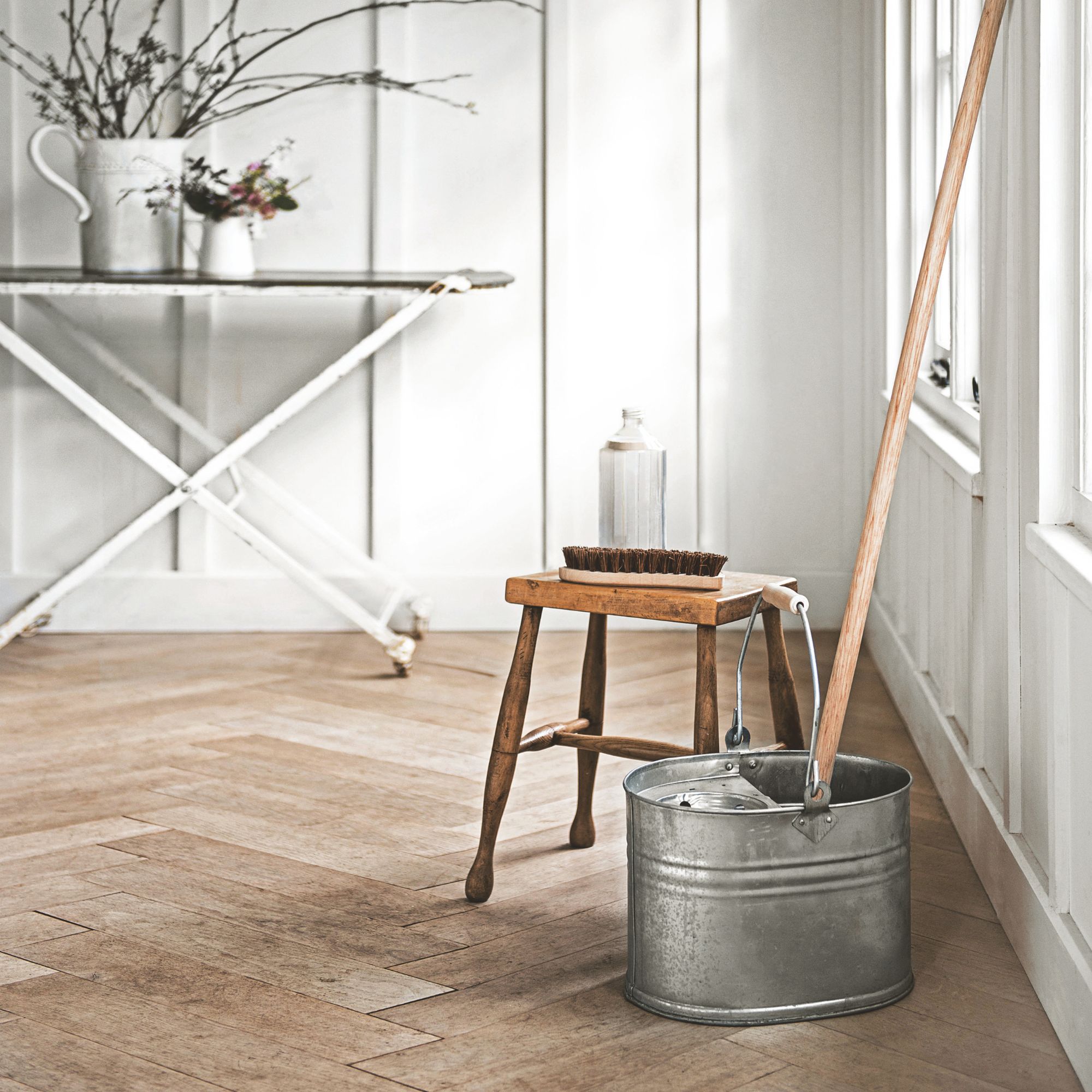 White room with wooden floor and a mop and bucket sitting on the floor