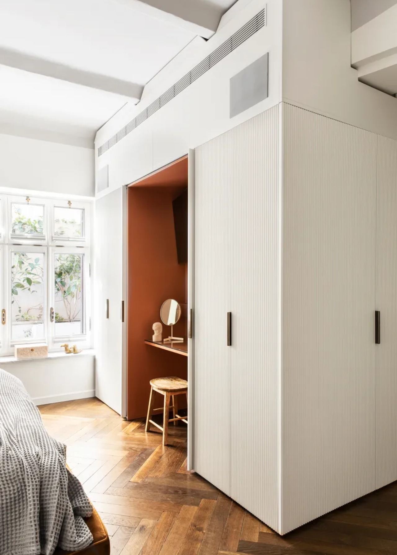 A bedroom with a vanity and white closet cupboards