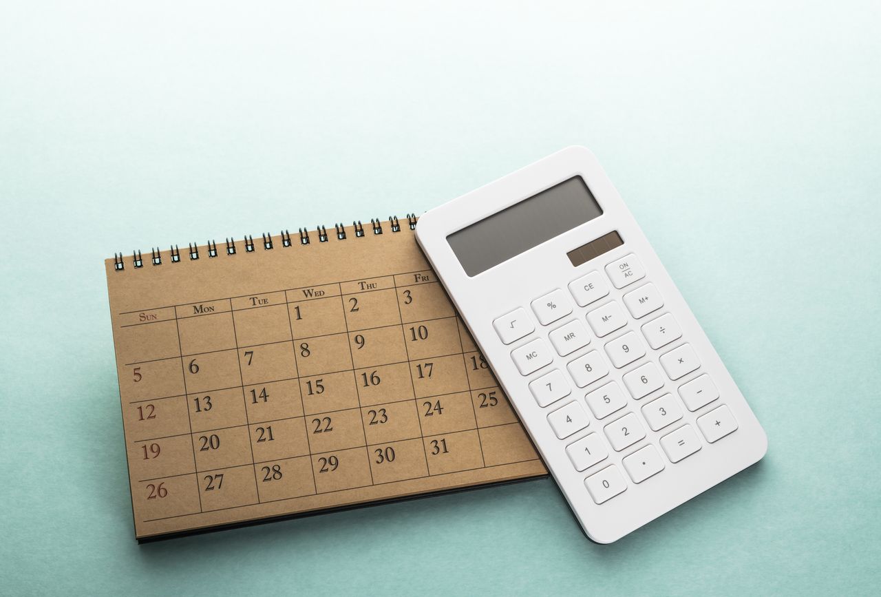 white calculator on top of spiral top calendar