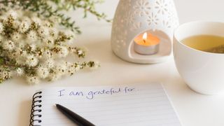 A gratitude journal with a candle burning