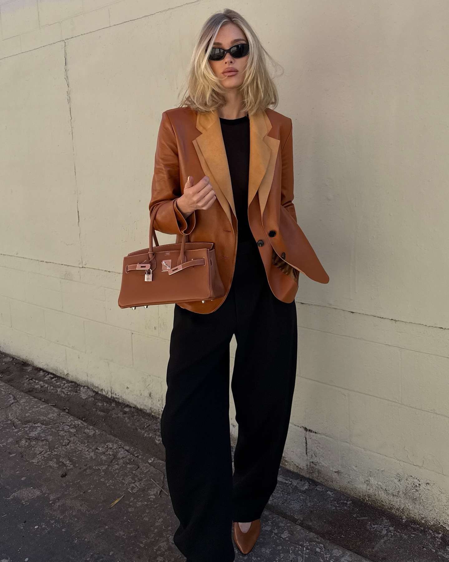 Elsa Hosk wearing a tobacco brown leather blazer from The Row with a matching Herm&amp;egrave;s Birkin bag and black pants.
