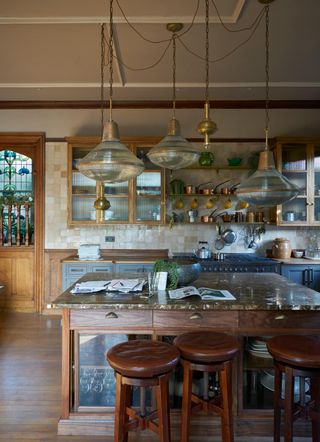 kitchen with wooden detailing and a cream-tiled backsplash. There are five glass pendant lights hanging above the island