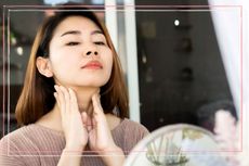 close up of an asian woman touching and admiring her neck in a mirror 