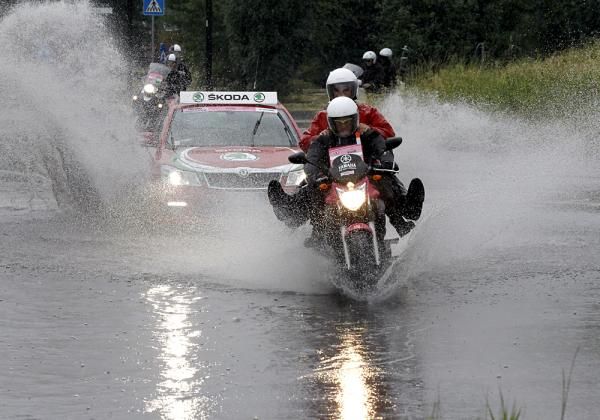 A motorcycle heads through a deep puddle